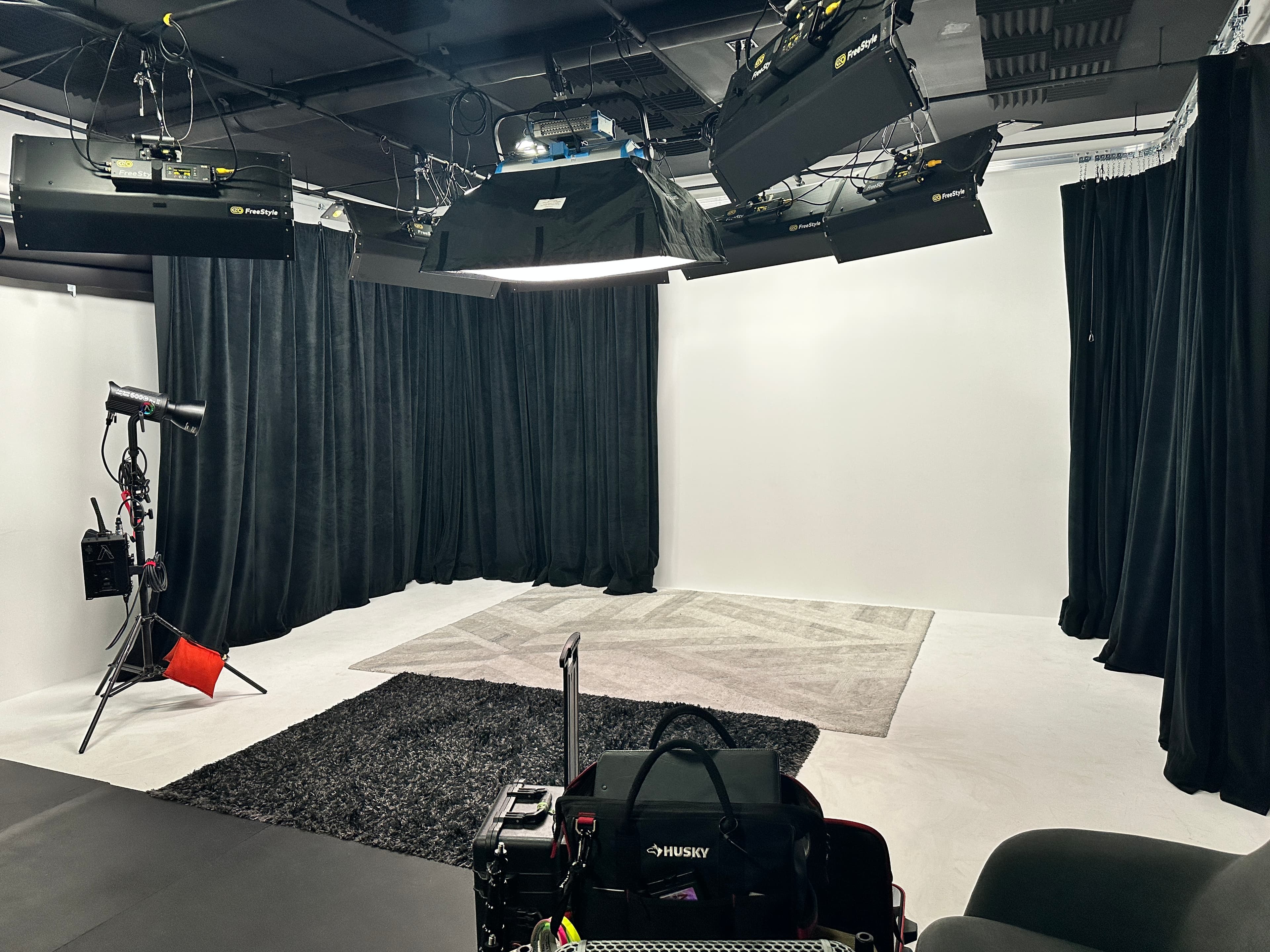 Media Bar Productions studio stage with white walls, black curtains, and an overhead lighting grid